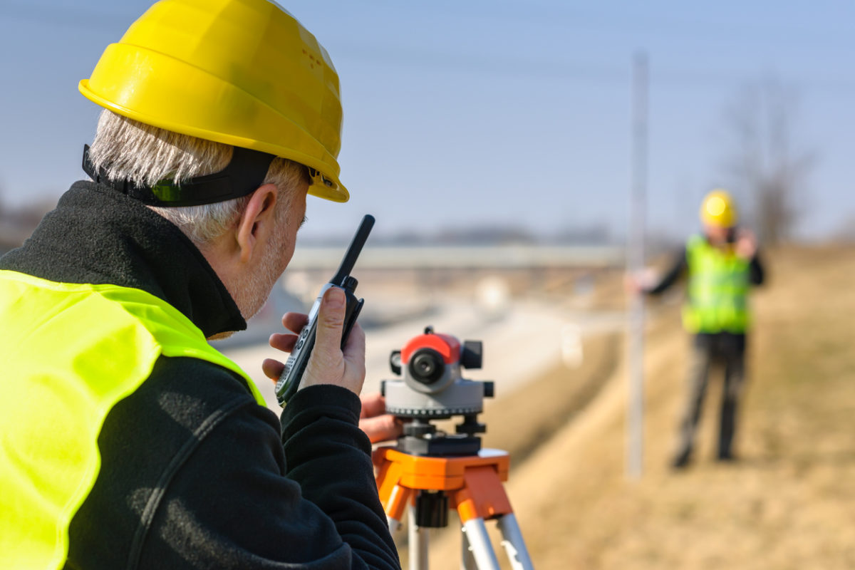 Two surveyors in reflective gear and tools outdoors - Votex Surveying